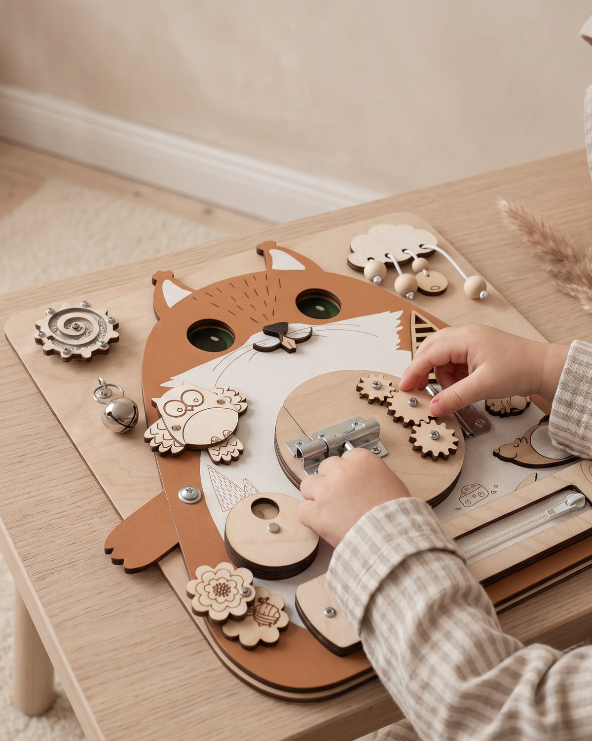 A toddler turning the gears on a wooden busy board