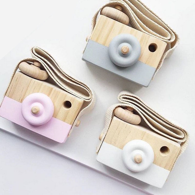 Three wooden toy cameras in pink, gray and white with straps
