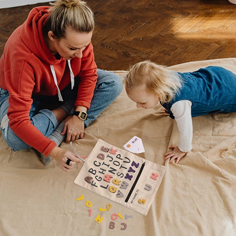 Parent and toddler playing with the ABC letter canvas board on the floor