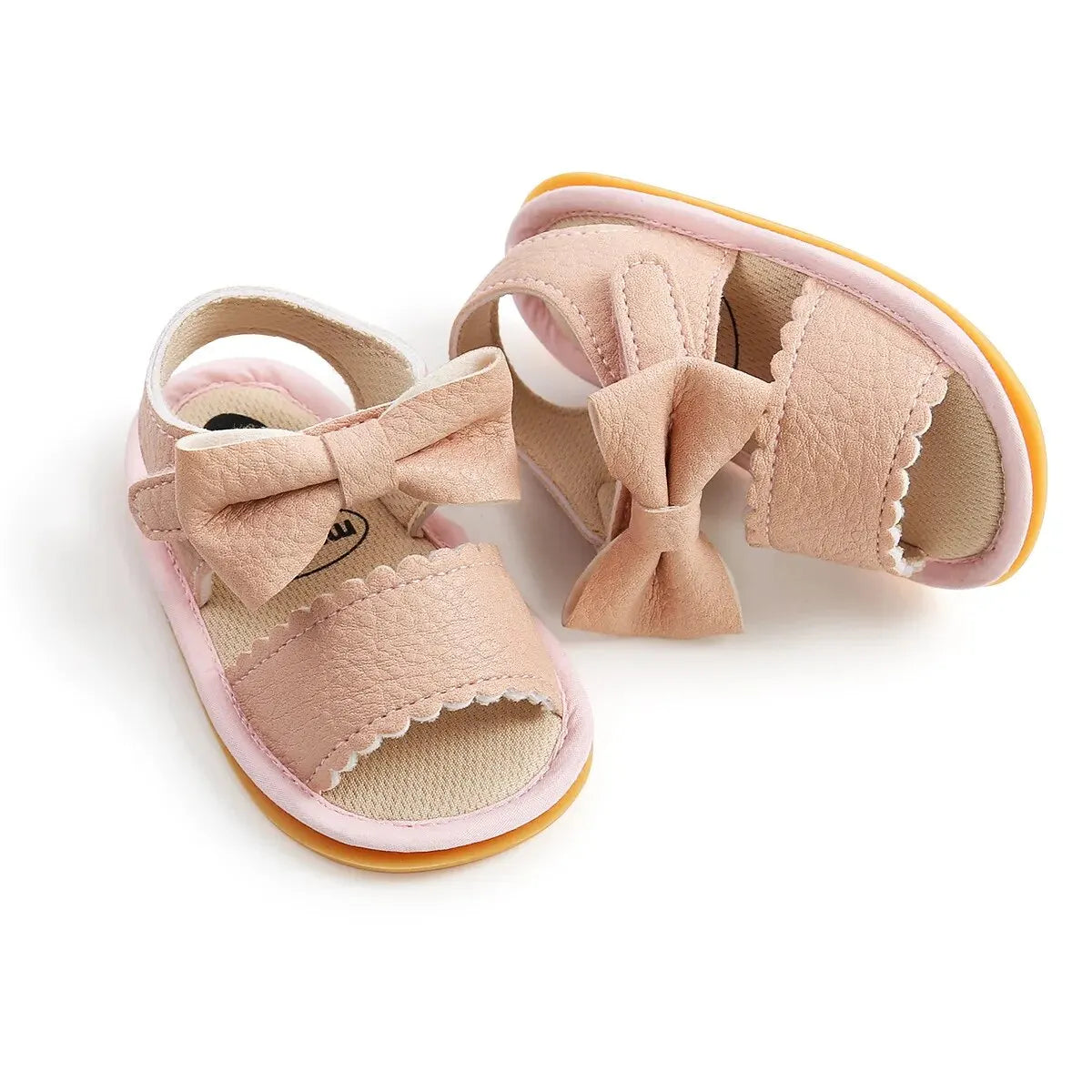 A cute pair of Bubebaby BabyLove  faux leather sandals for infants featuring an adorable bow detail. The sandals are designed for comfort and style, perfect for little ones to wear during warm weather. The adjustable strap ensures a secure fit while the soft sole provides cushioning for tiny feet