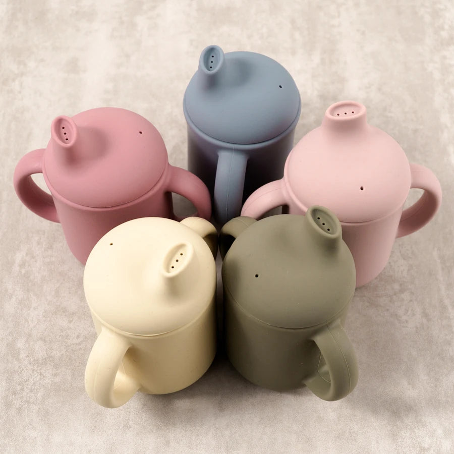 Five silicone sippy cups grouped together with spout lids on