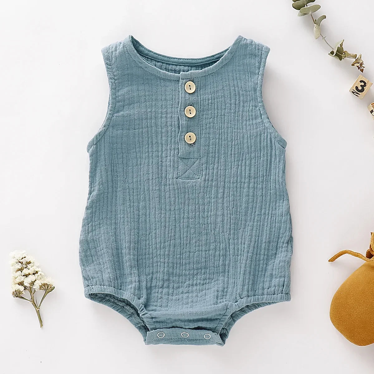 the BabyLove Sleeveless Romper at BubeBaby, designed for babies 0-24 months. Made from soft cotton, this solid-colored romper features an O-neck and covered button closure, perfect for summer