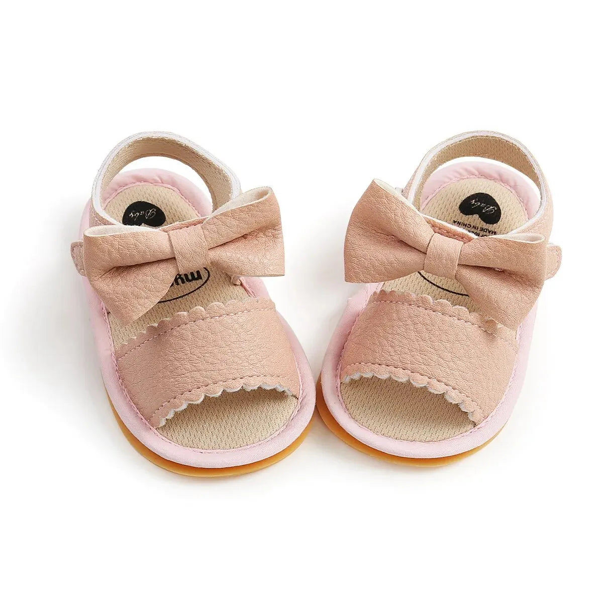 A cute pair of Bubebaby BabyLove  faux leather sandals for infants featuring an adorable bow detail. The sandals are designed for comfort and style, perfect for little ones to wear during warm weather. The adjustable strap ensures a secure fit while the soft sole provides cushioning for tiny feet