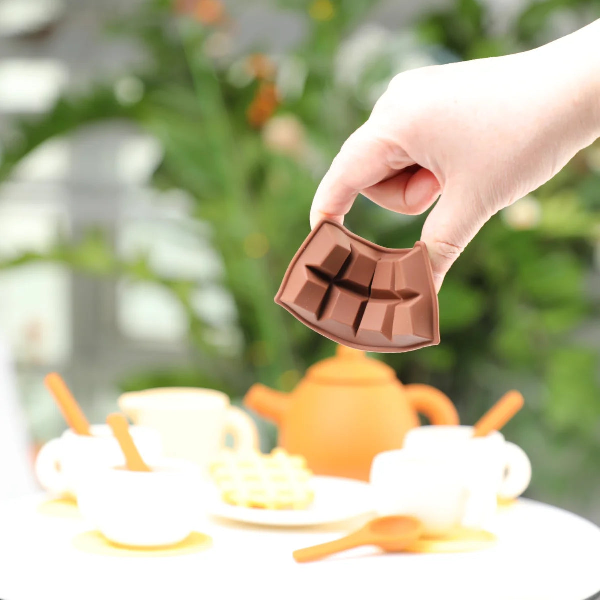 Hand holding the silicone chocolate bar above the tea set
