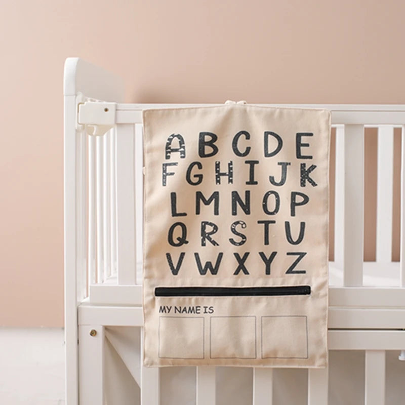 ABC letter canvas bag hanging from a white cot rail