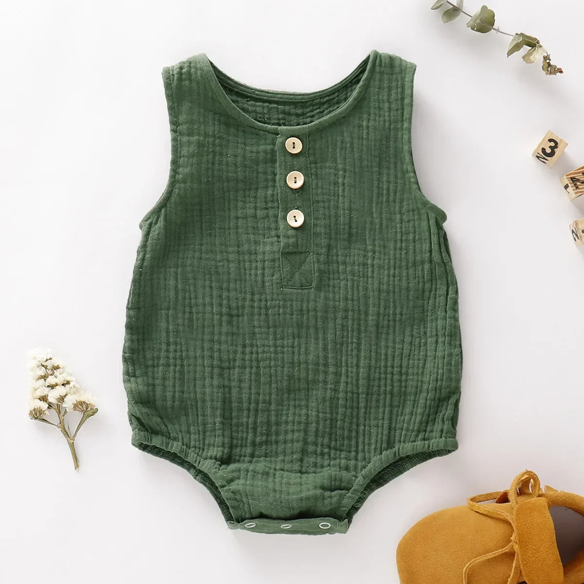 the BabyLove Sleeveless Romper at BubeBaby, designed for babies 0-24 months. Made from soft cotton, this solid-colored romper features an O-neck and covered button closure, perfect for summer