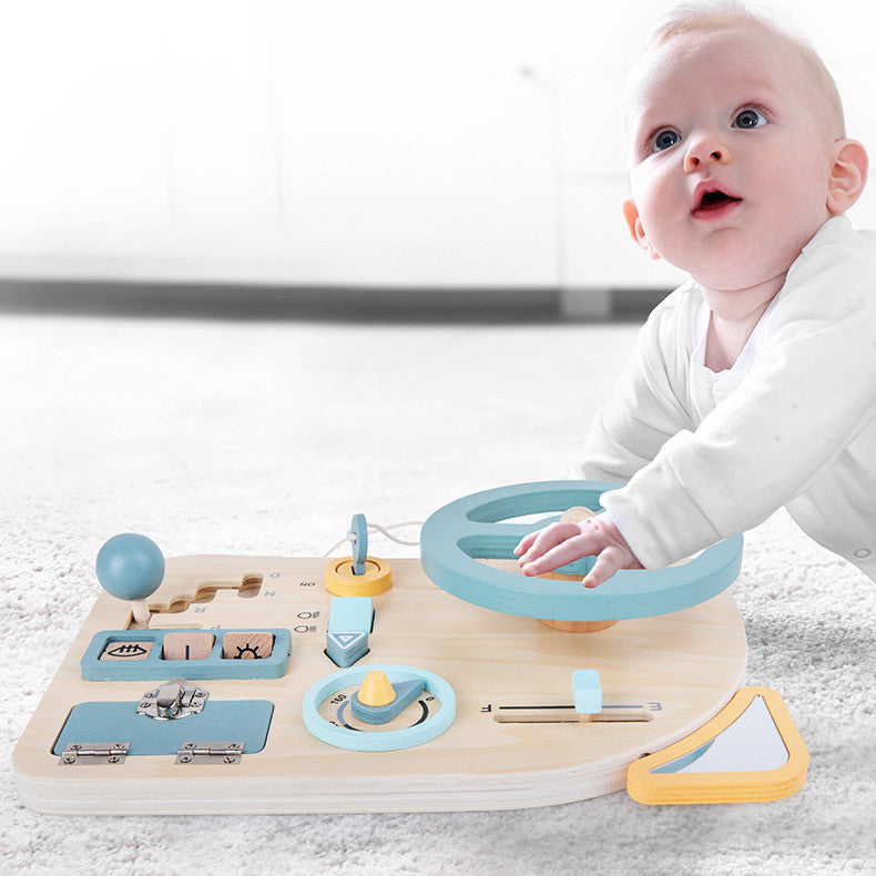 Baby playing with a wooden steering wheel busy board
