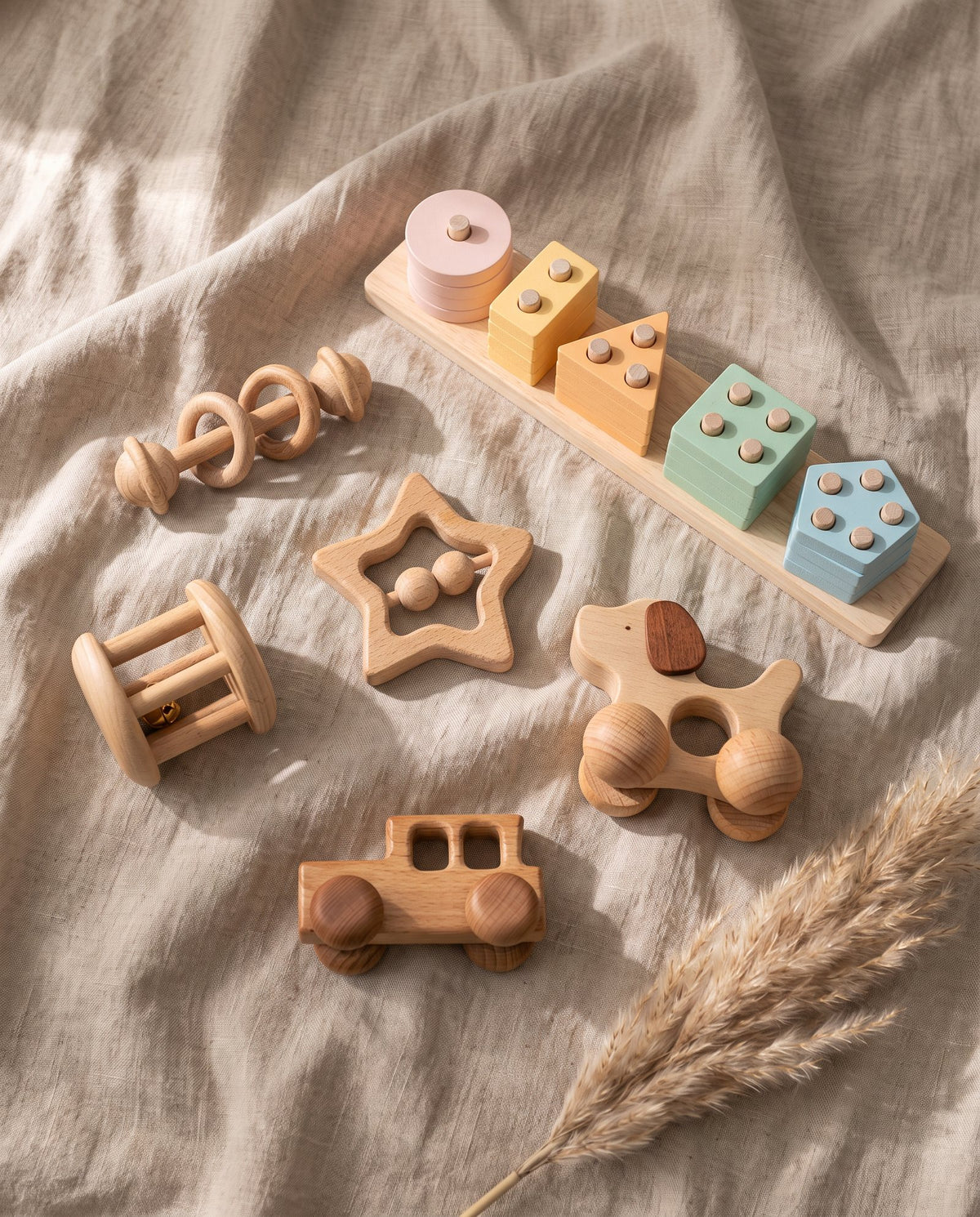 Wooden rattles, a wooden car, a puppy push toy and a pastel shape stacker on linen