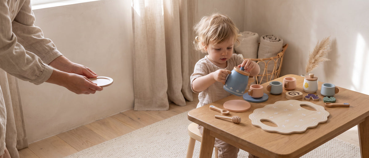 A toddler pouring from a wooden teapot at a small table