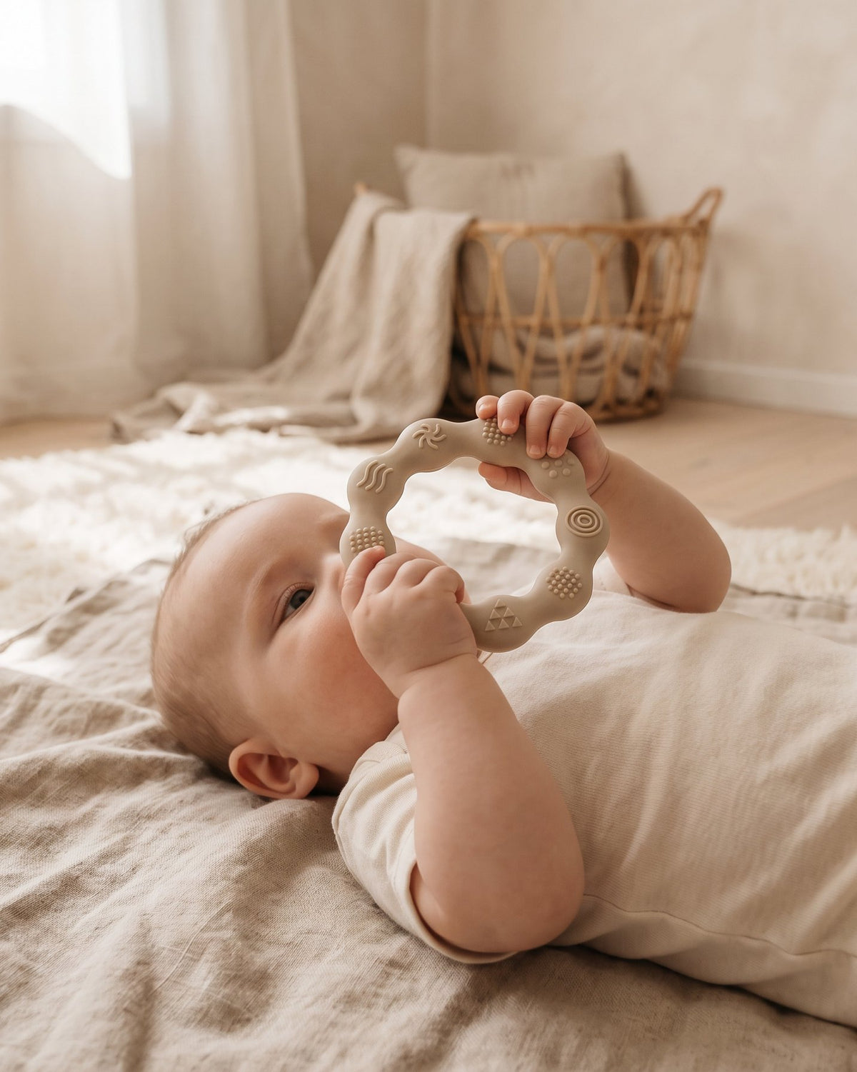 A baby holding a silicone ring teether