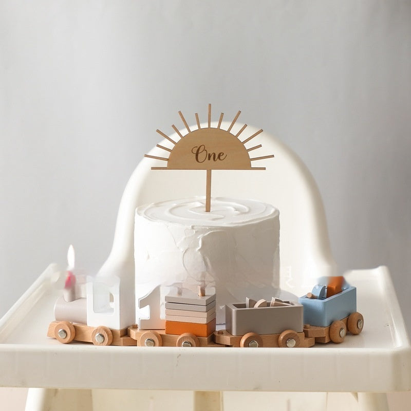 Wooden birthday train with a first birthday cake on a high chair